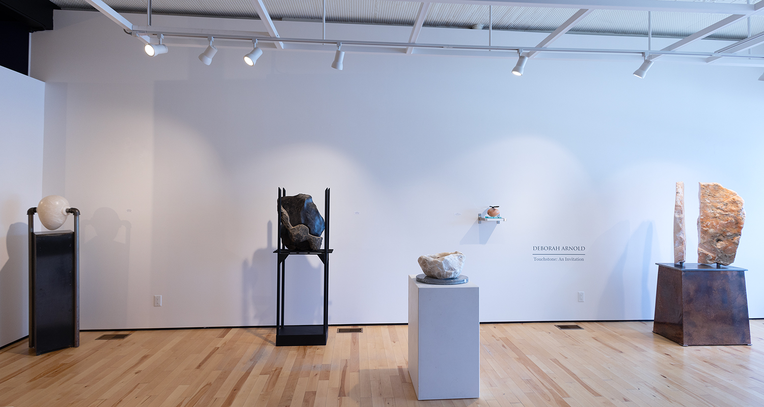 Sculptures sit on pedestals against a white wall in a gallery