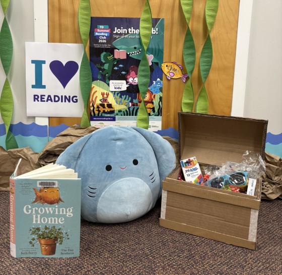 A display in the Mississippi Mills Public Library promoting the TD Summer Reading Club 2026. It includes an 'I Love Reading' sign, a book, treasure chest and stingray Squishmallow.