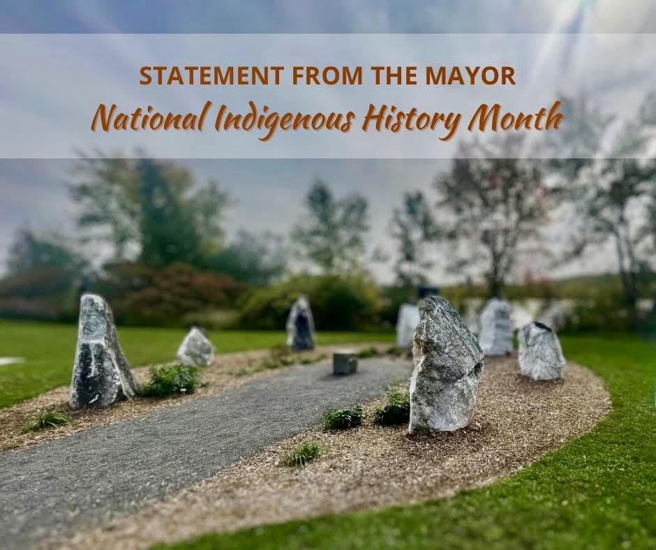 A cluster of rocks formed in a semi circle in a park. Orange text reads 'Statement from the Mayor - National Indigenous History Month.'