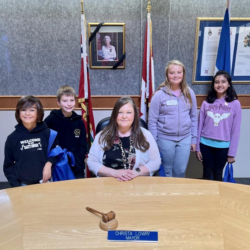 Mayor Christa Lowry sits at the council table surrounded by students
