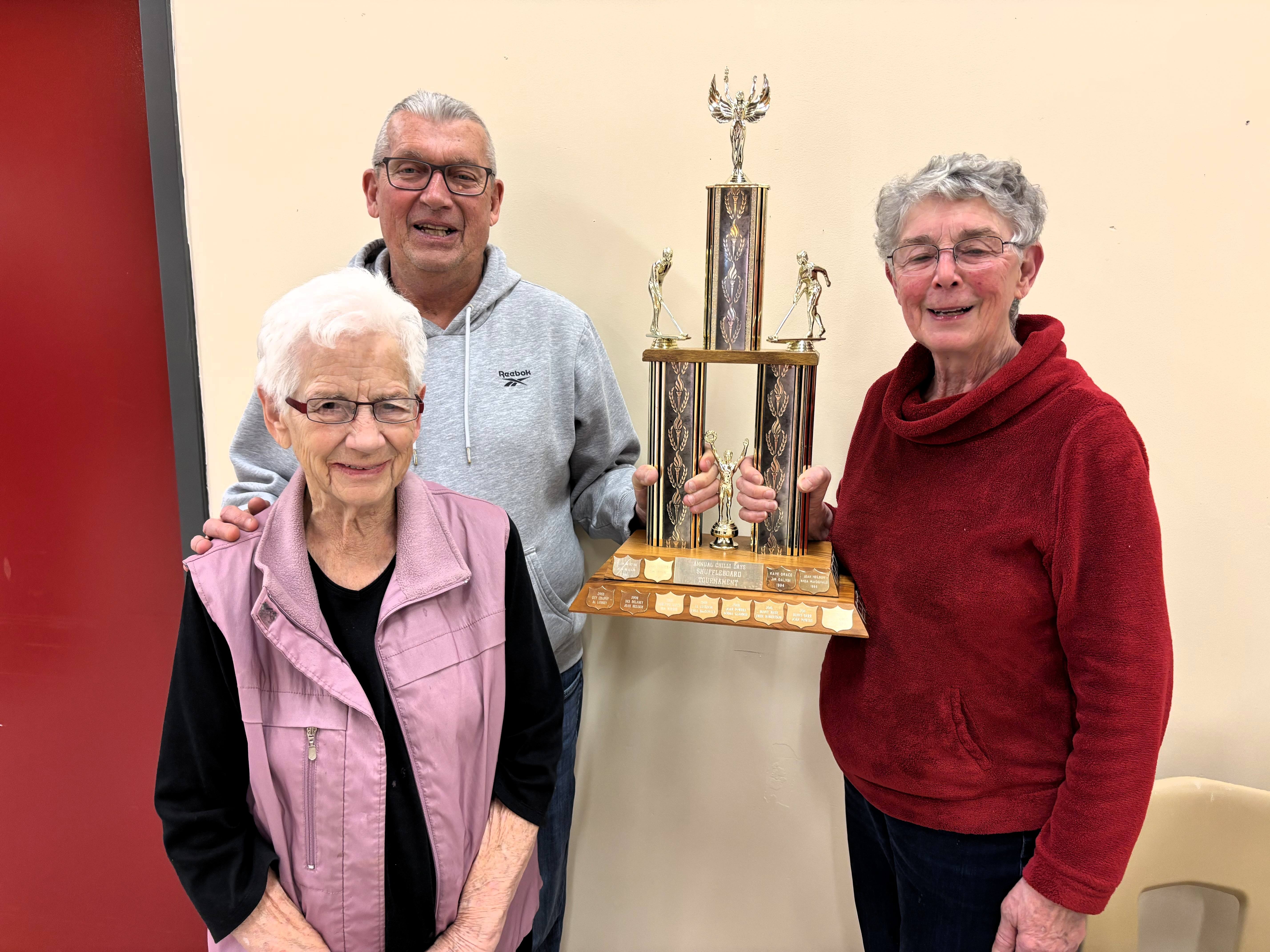Three people pose for a photo with a trophy