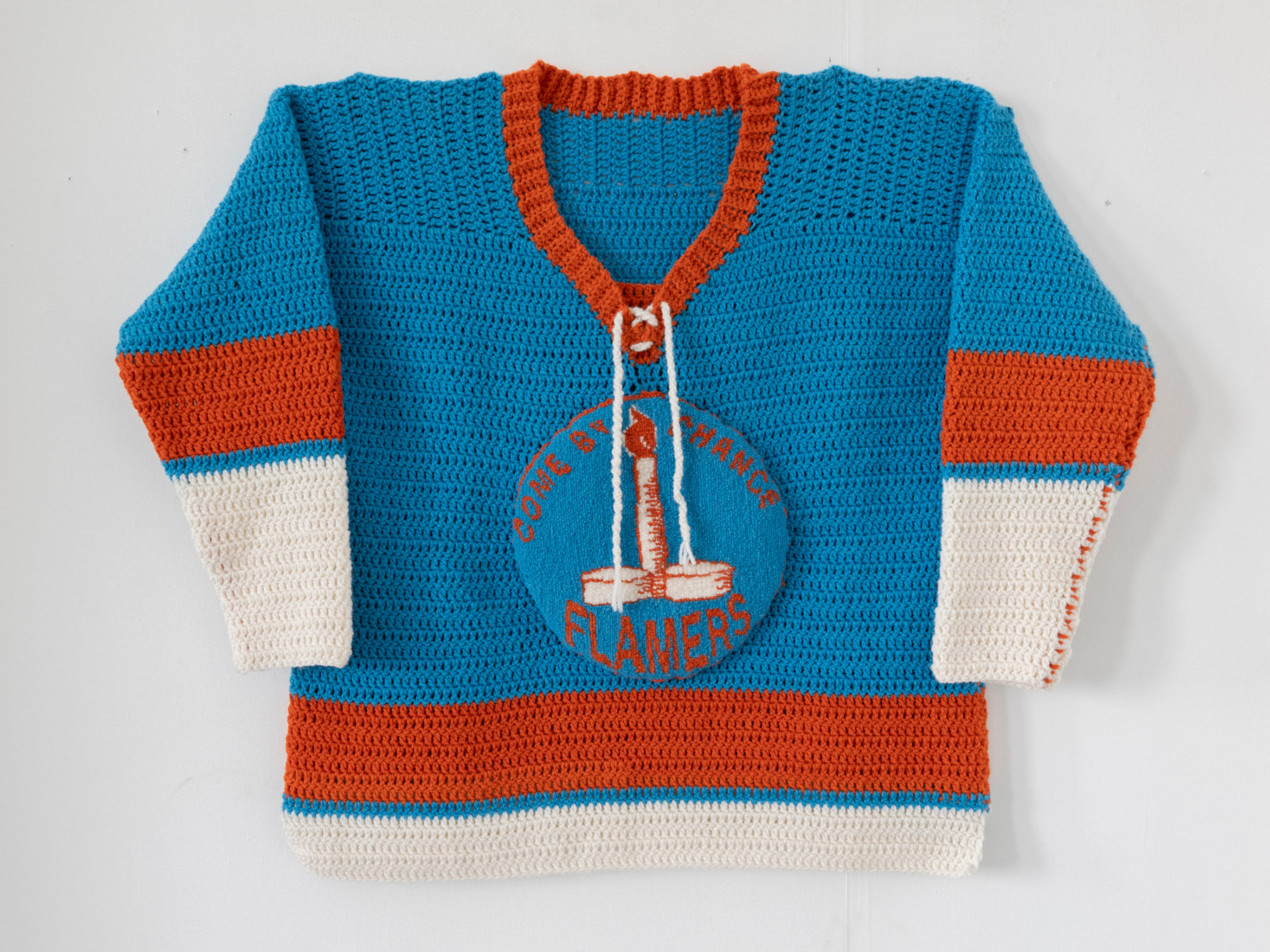 A crocheted hockey sweater in blue, orange and white colours