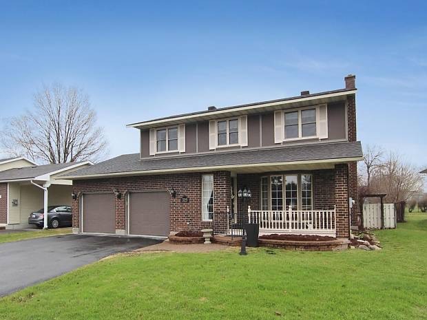 A brown brick house with two garages behind a green lawn