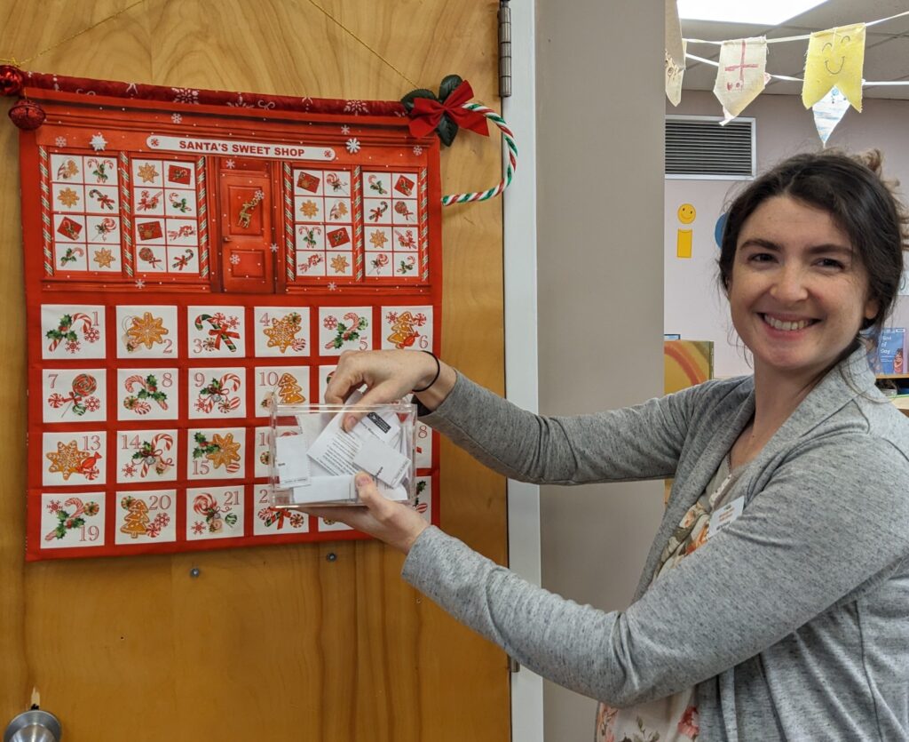 Woman stands next to a door displaying a Christmas advent calendar
