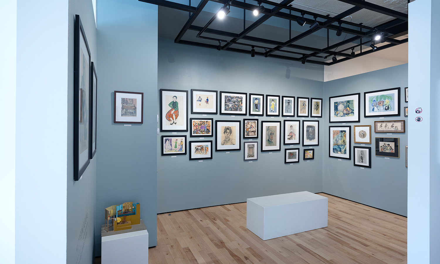 A gallery space with pale blue walls covered with framed photographs