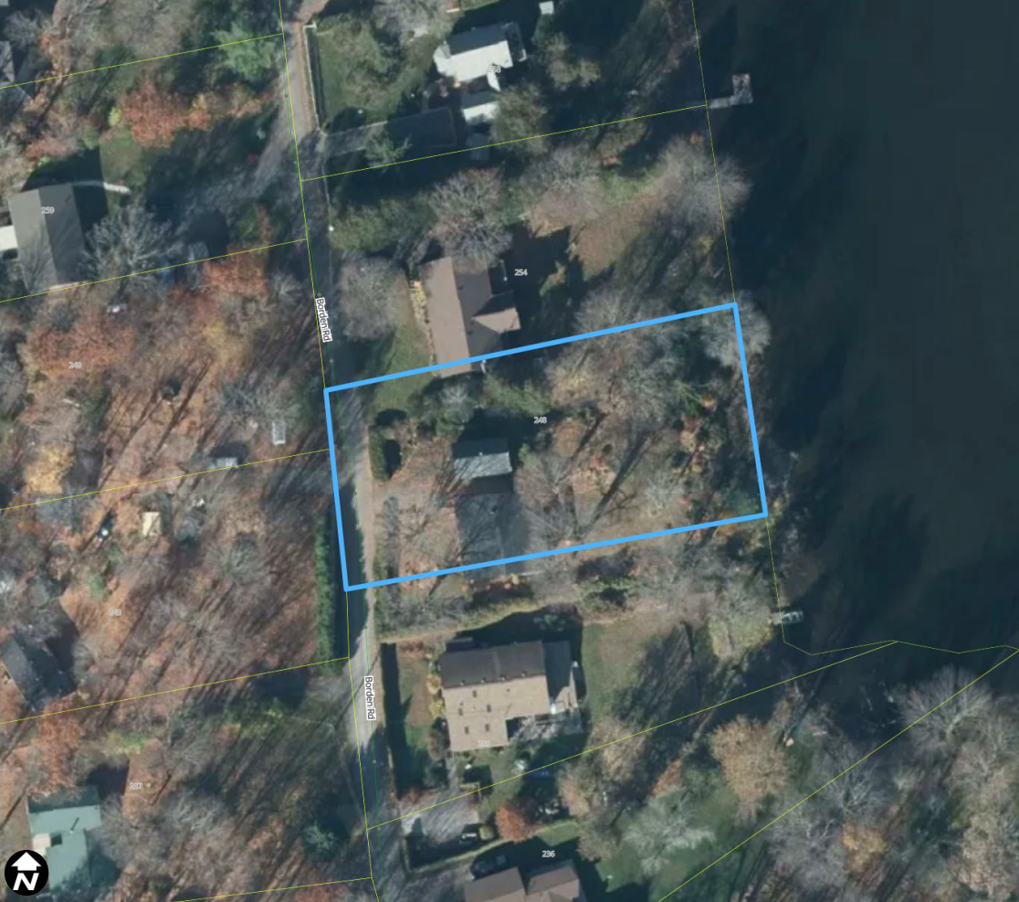 Satellite image of a rural area, with homes and trees surrounding it. A light blue box outlines a property.