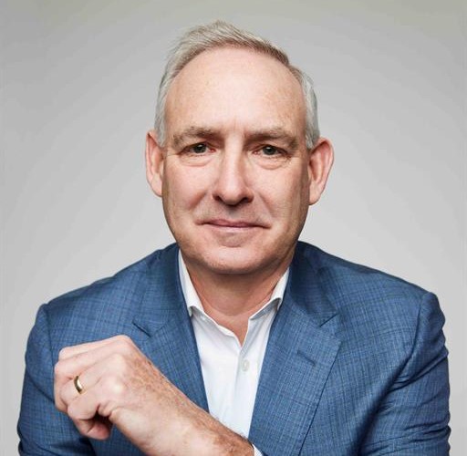 Silver-haired man in blue suit looks at camera