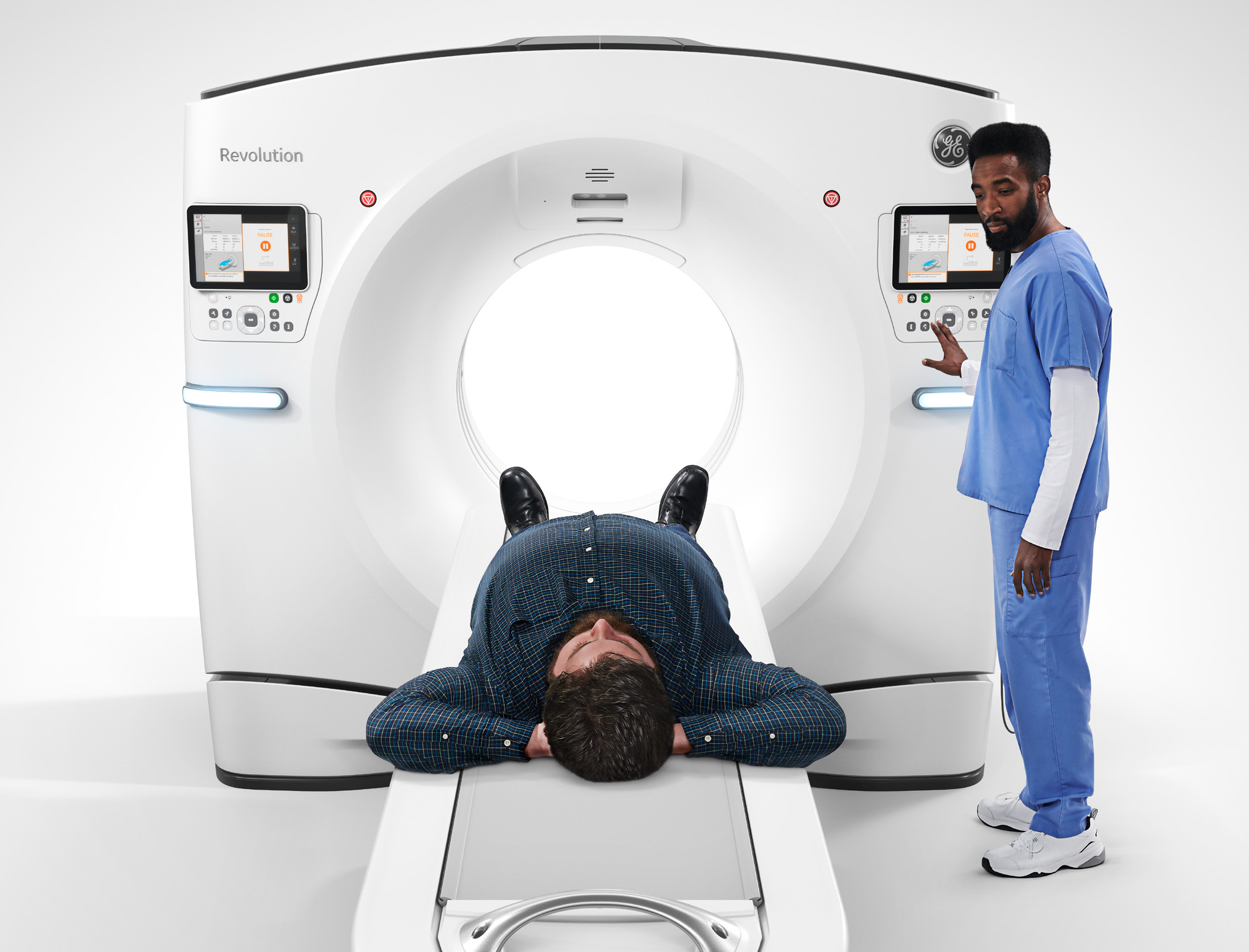 Person prepares to enter CT scanner as nurse stands next to the machine at the controls