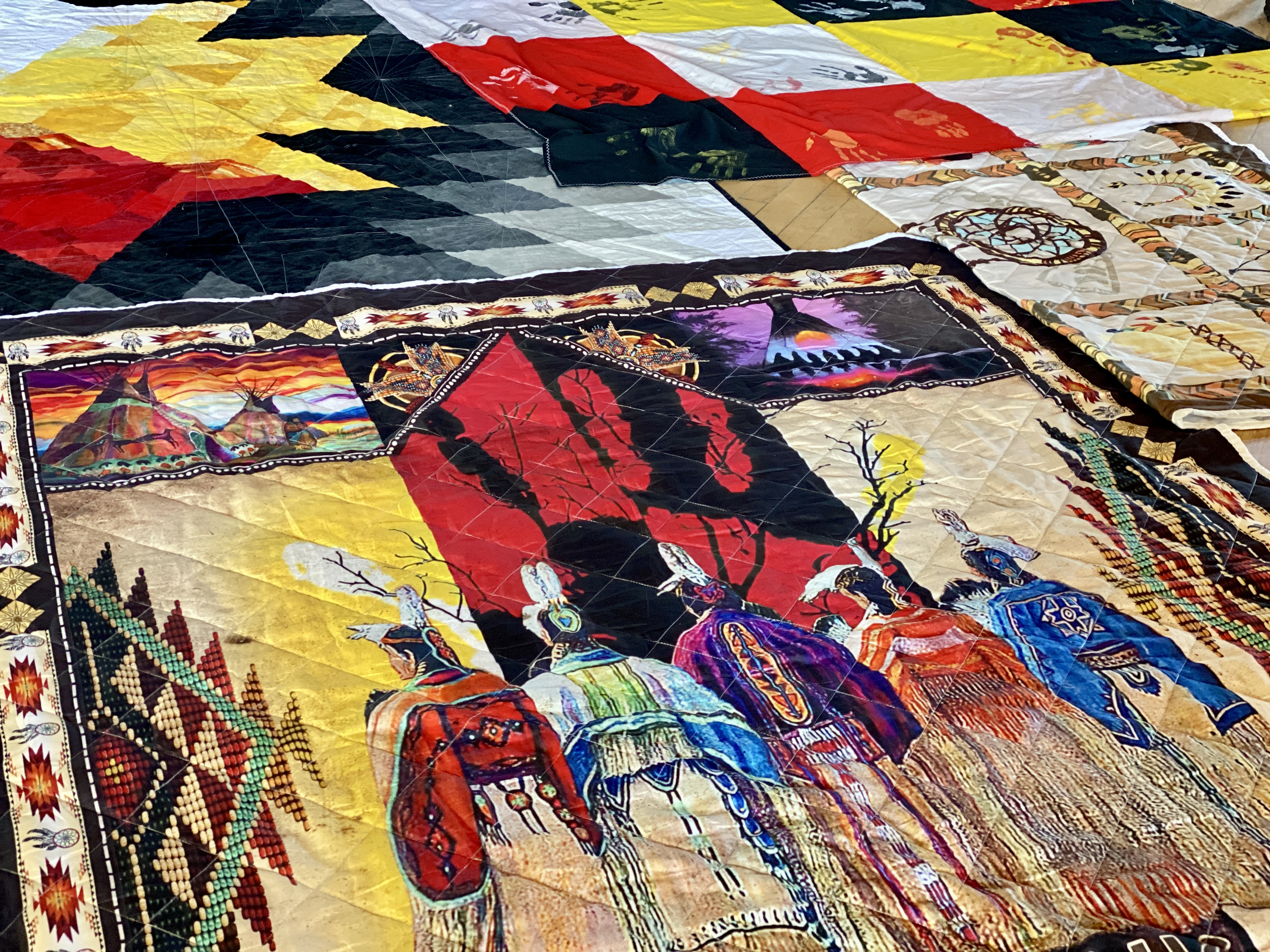Photo of brightly coloured blankets spread out on a wood floor