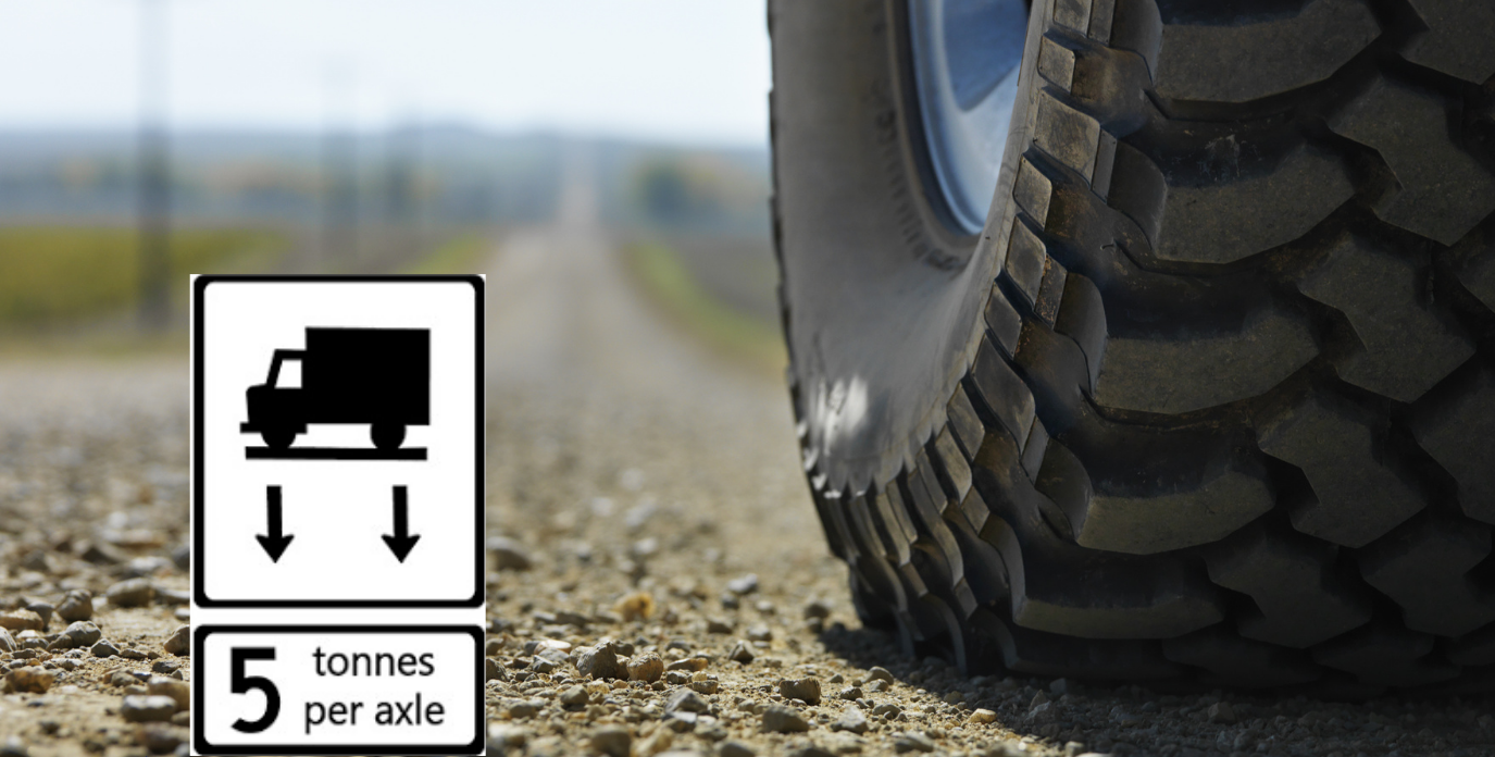 Close-up photo of a car's tire on a rural road with a black and white graphic reading '5 tonnes per axle'