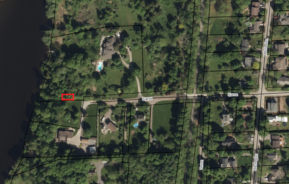Satellite view of a forested rural neighbourhood with an area marked in red.