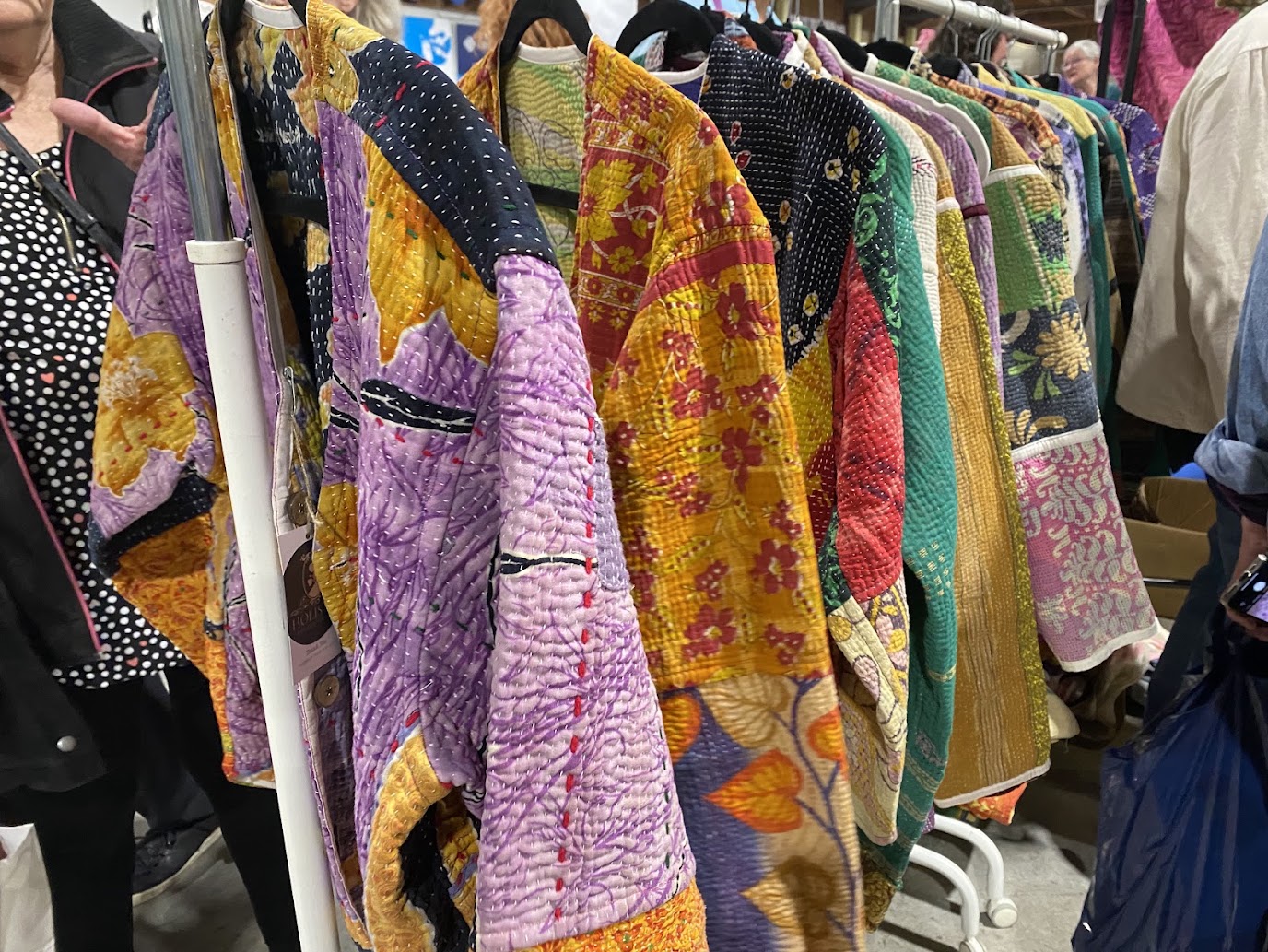 Colourful handmade sweaters hanging on a rack