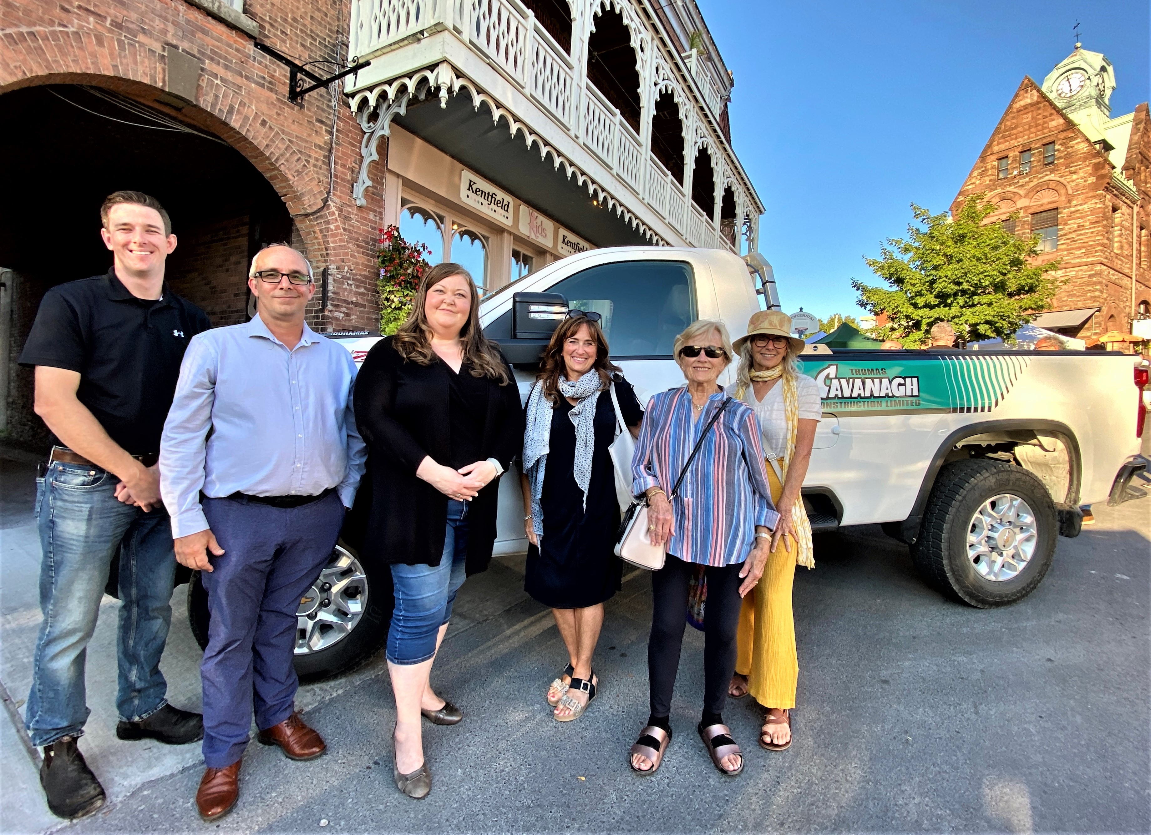 Group of people stand in front of a white truck