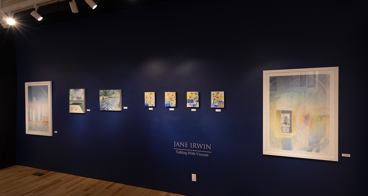 Canvases hang on a dark blue gallery wall