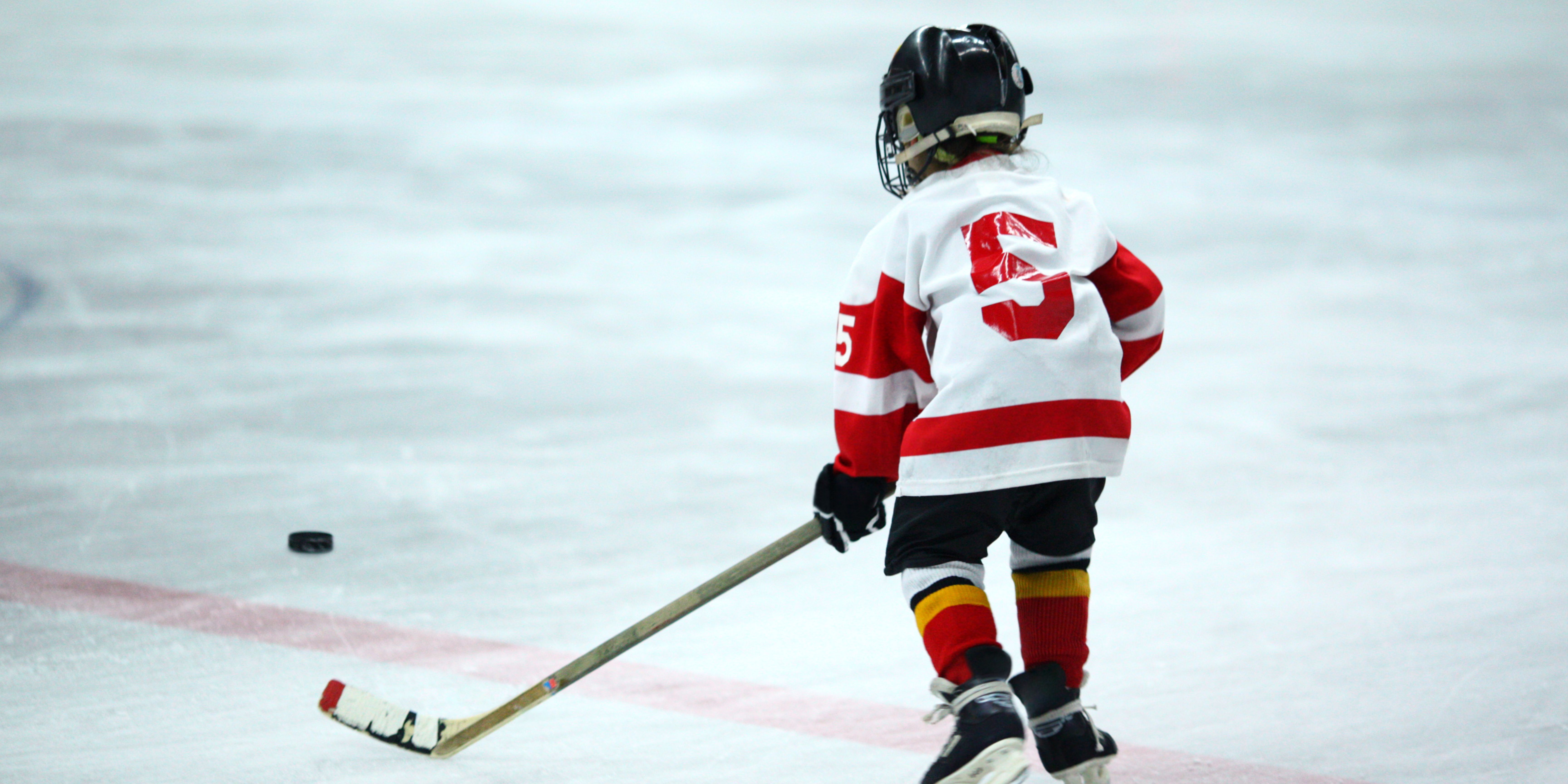Kid skating on ice rink with hockey gear