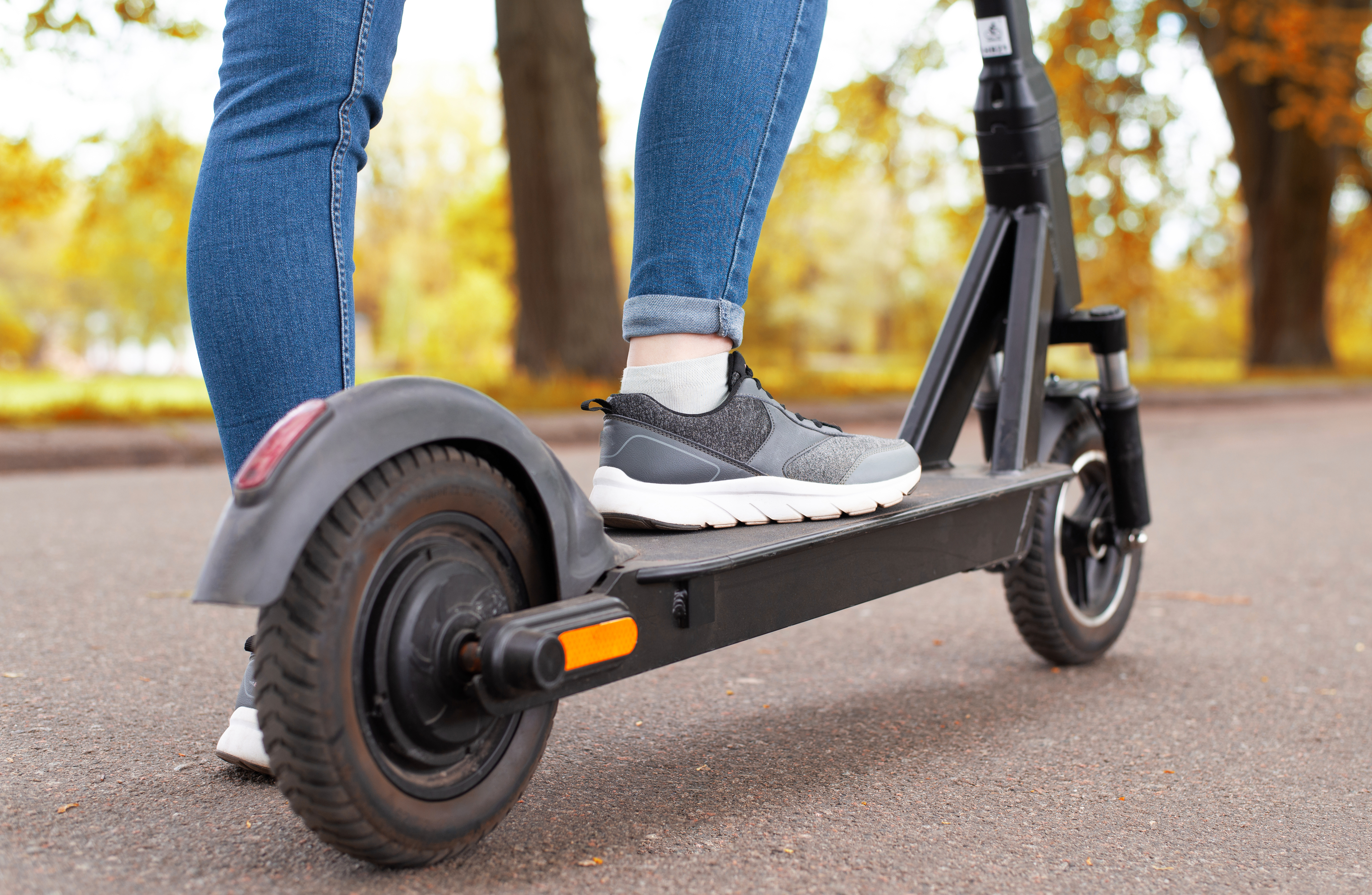 A womans feet wearing running shoes standing on a scooter