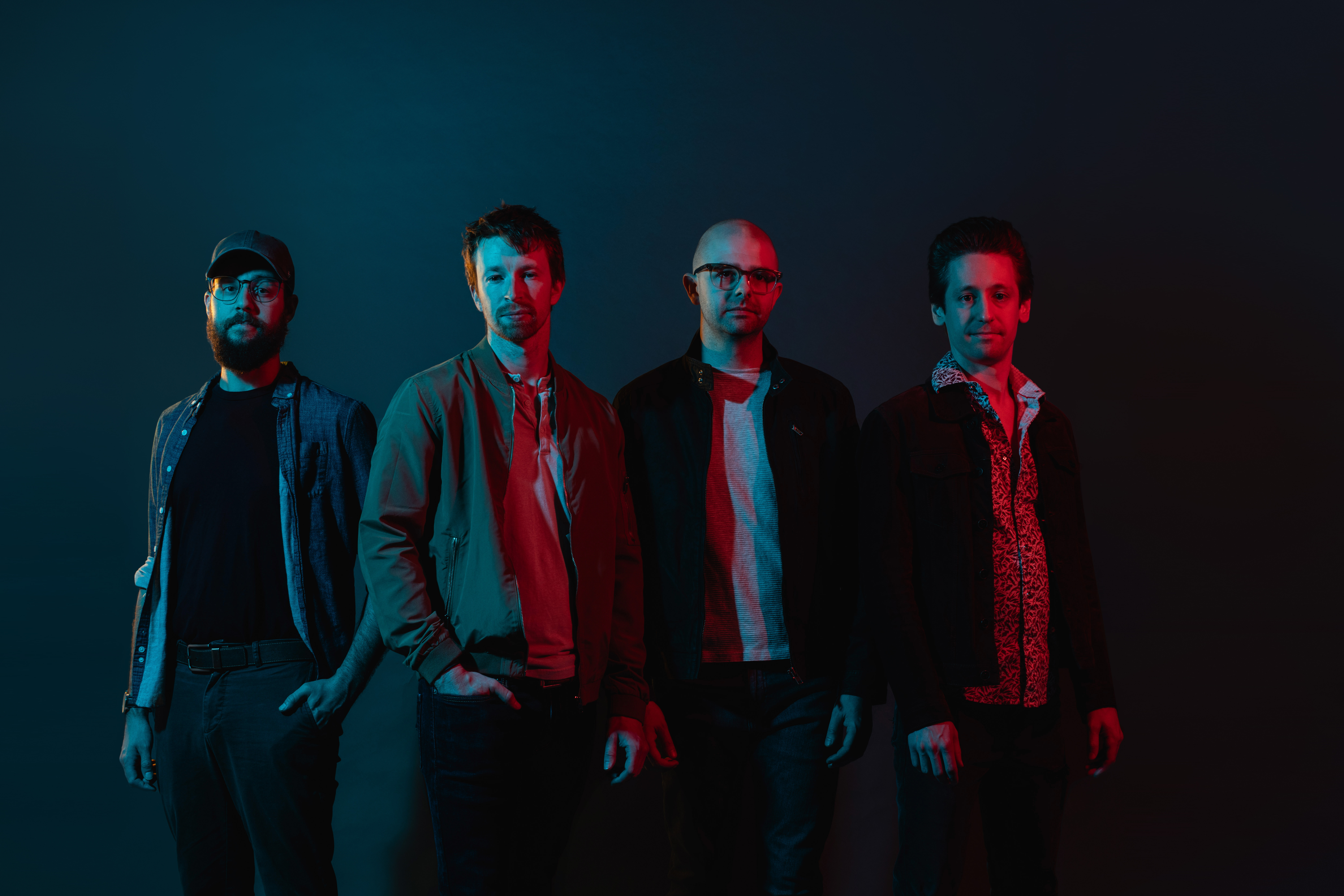four men in dim lighting posing