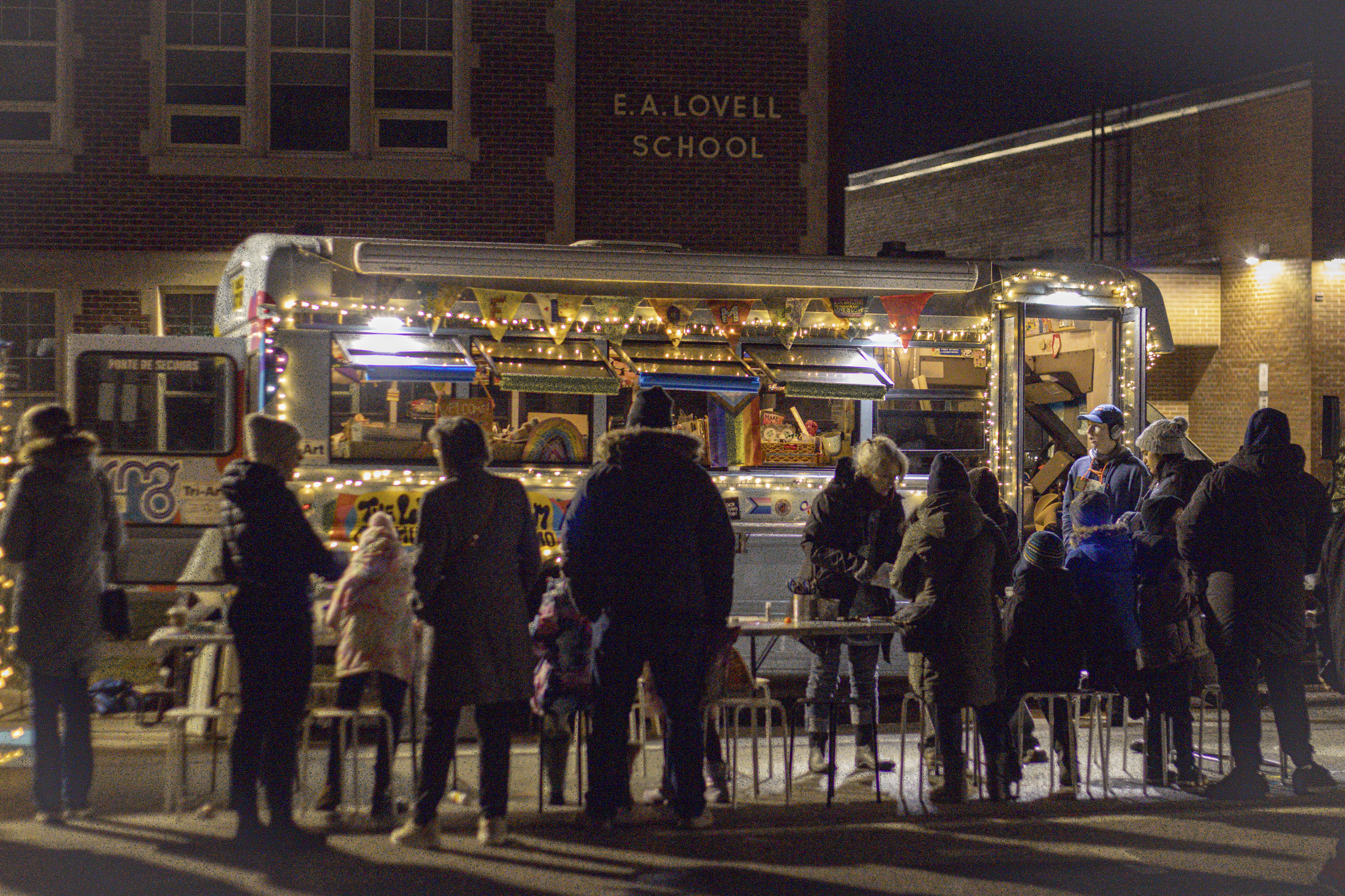 people crowded around art bus at night