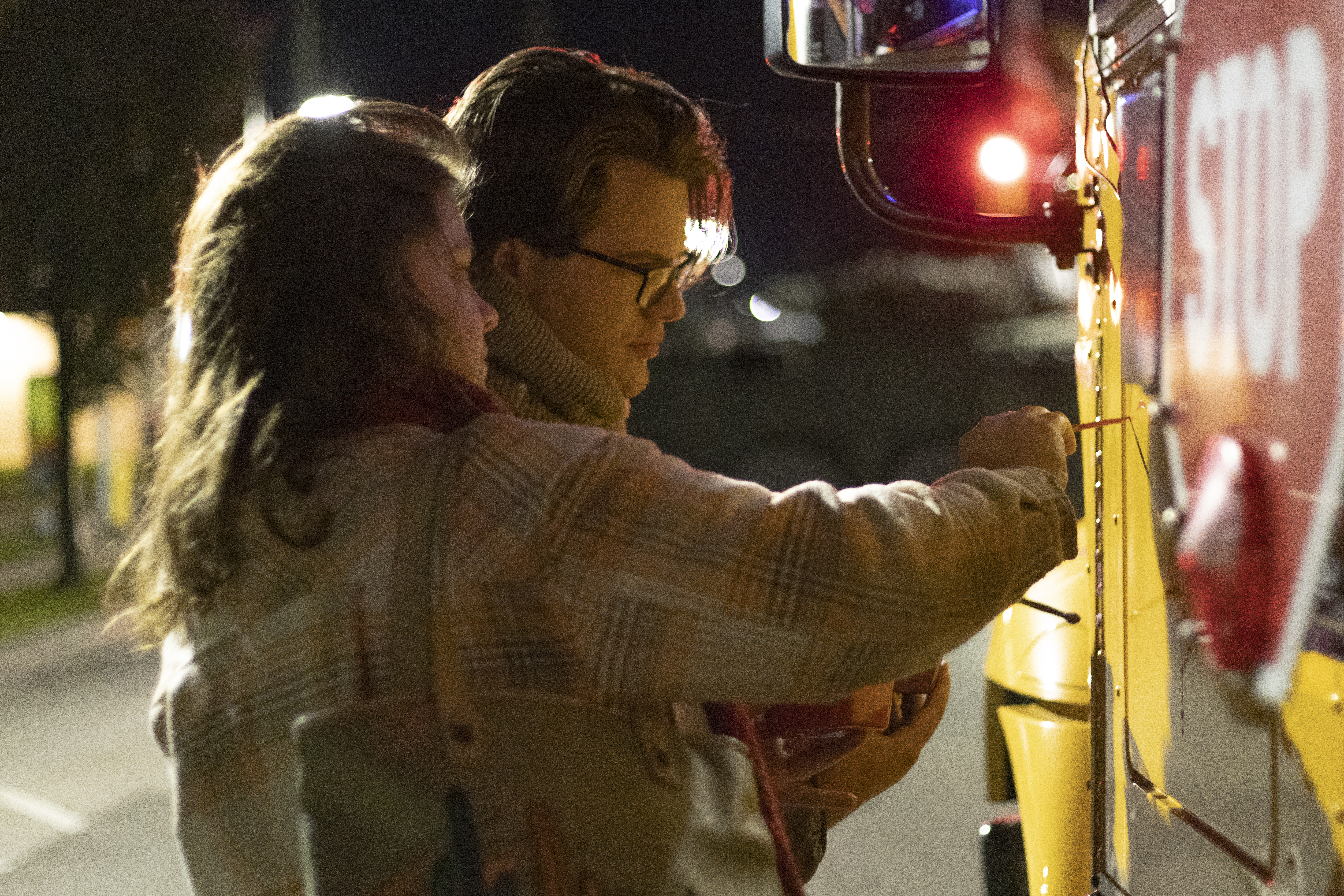 two people painting a bus at night