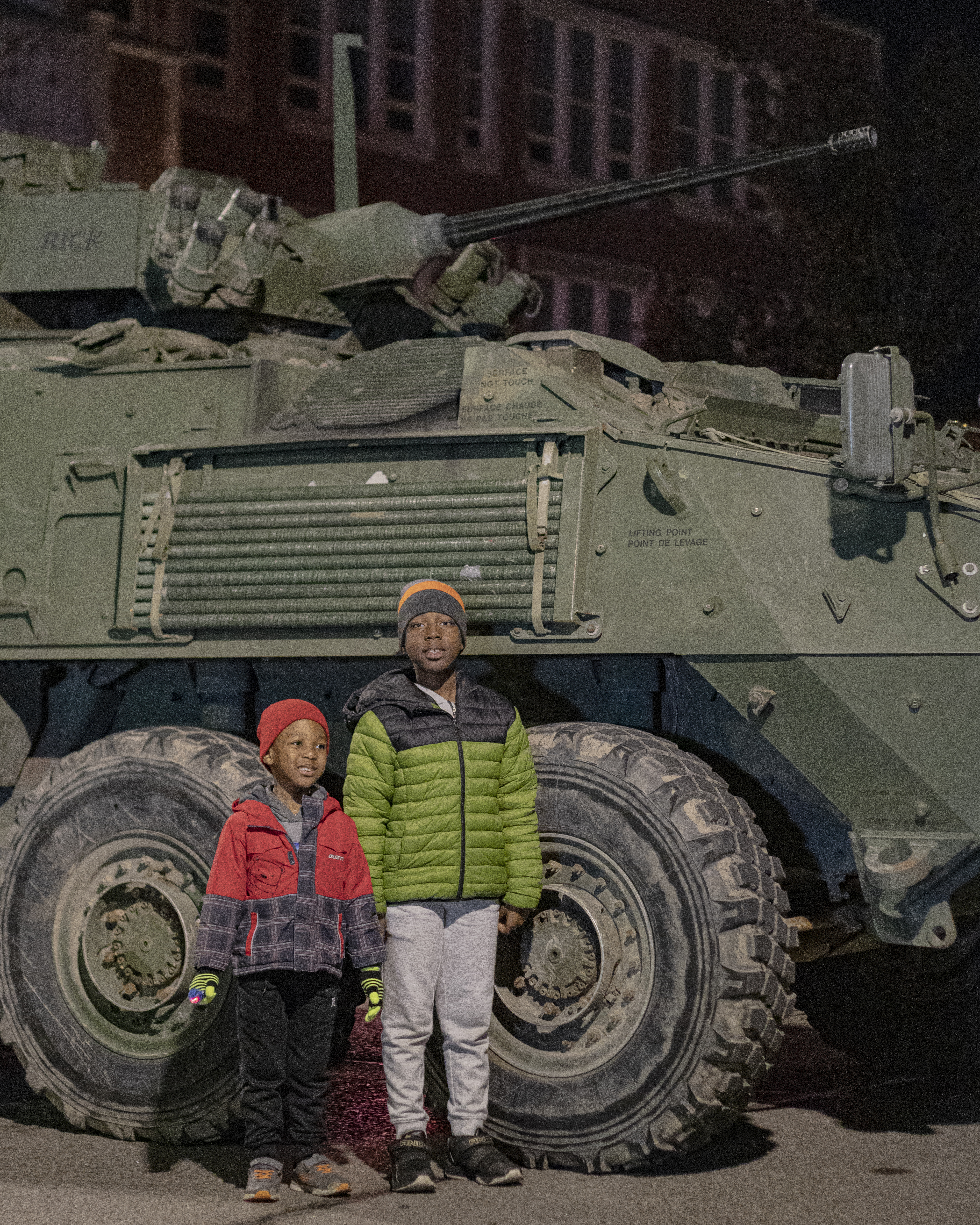 two children standing in front of tank