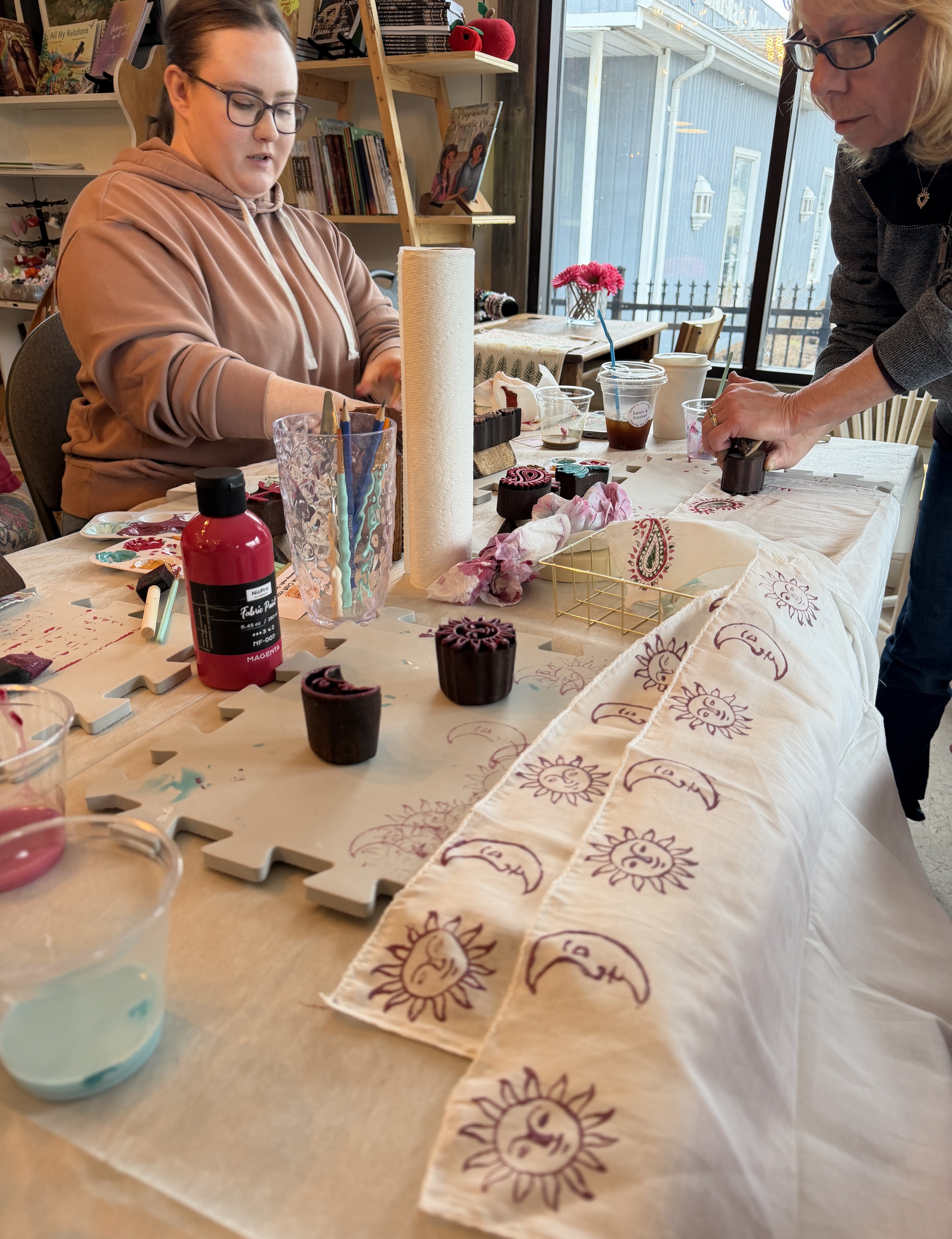 Two people participating in an art activity using blocks to paint on fabric