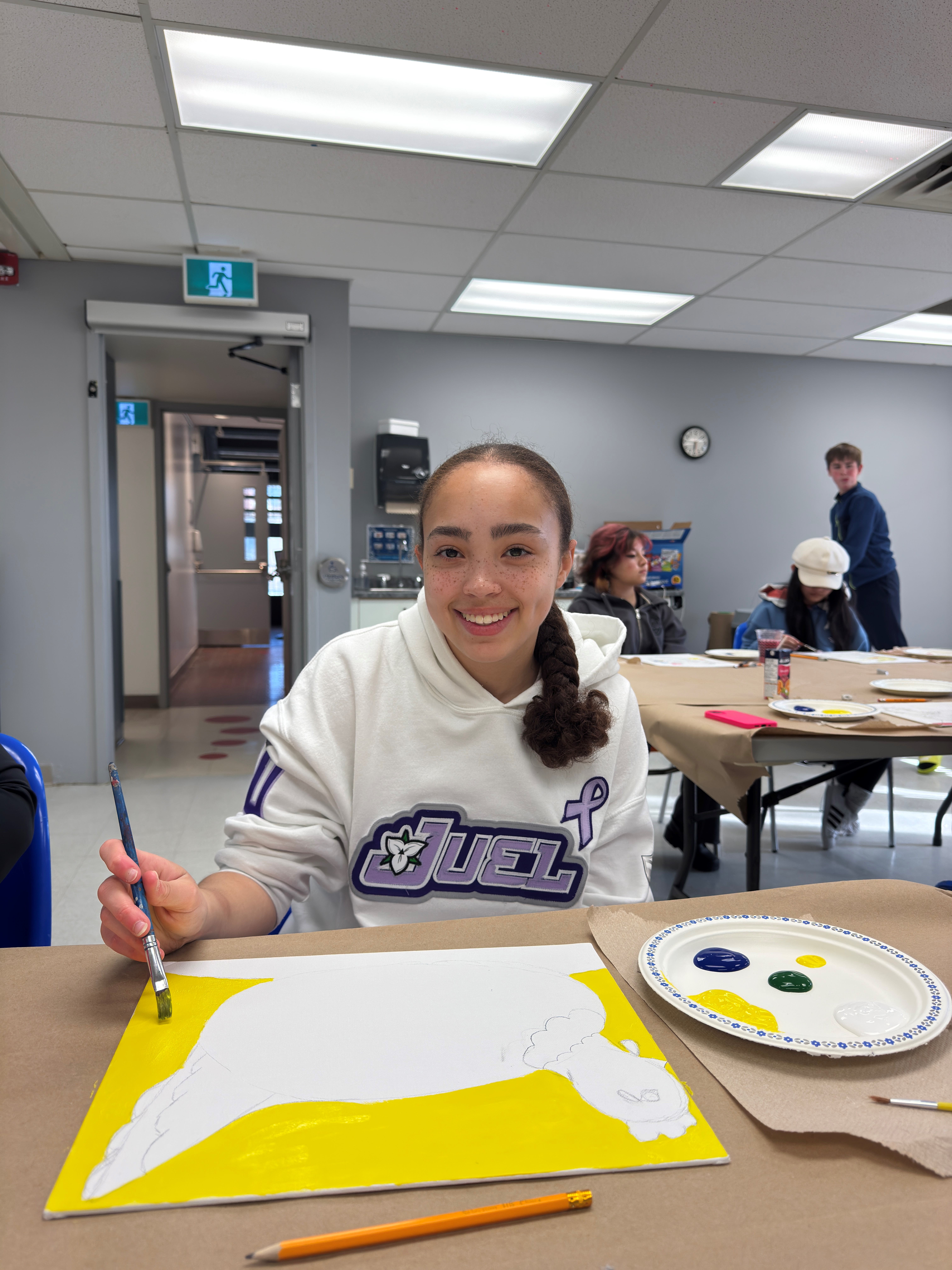 female youth painting and looking at camera 