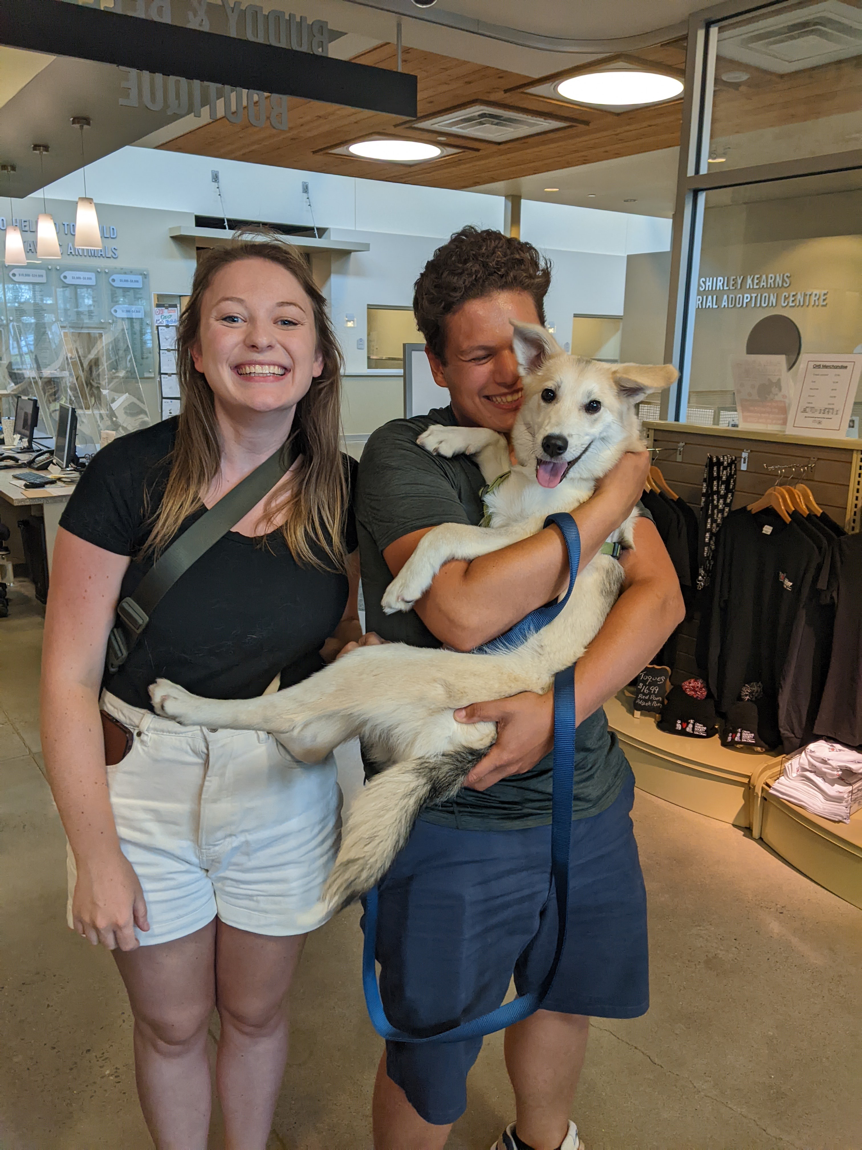 Woman and man embrace their newly adopted dog. 