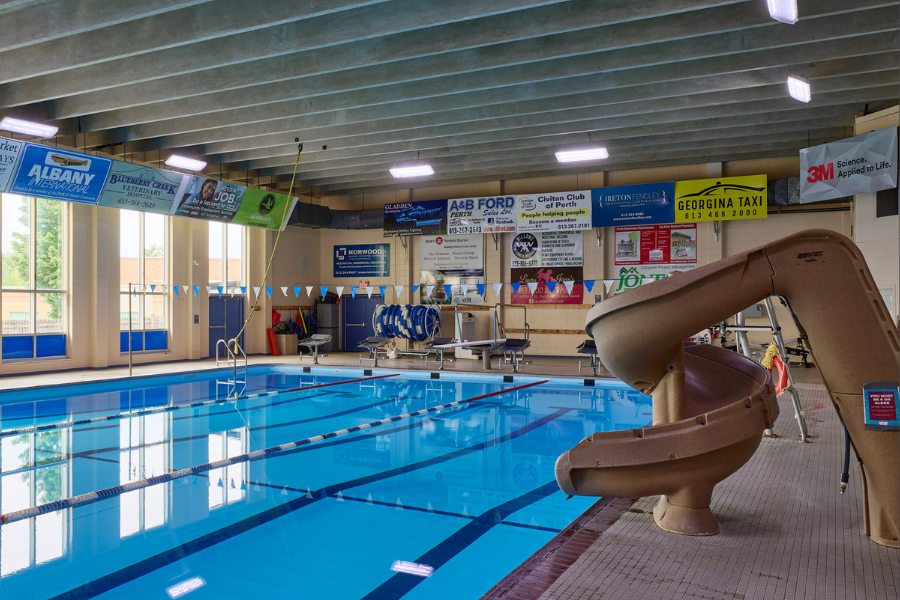 Indoor community pool looking towards deep end, with water slide on the right