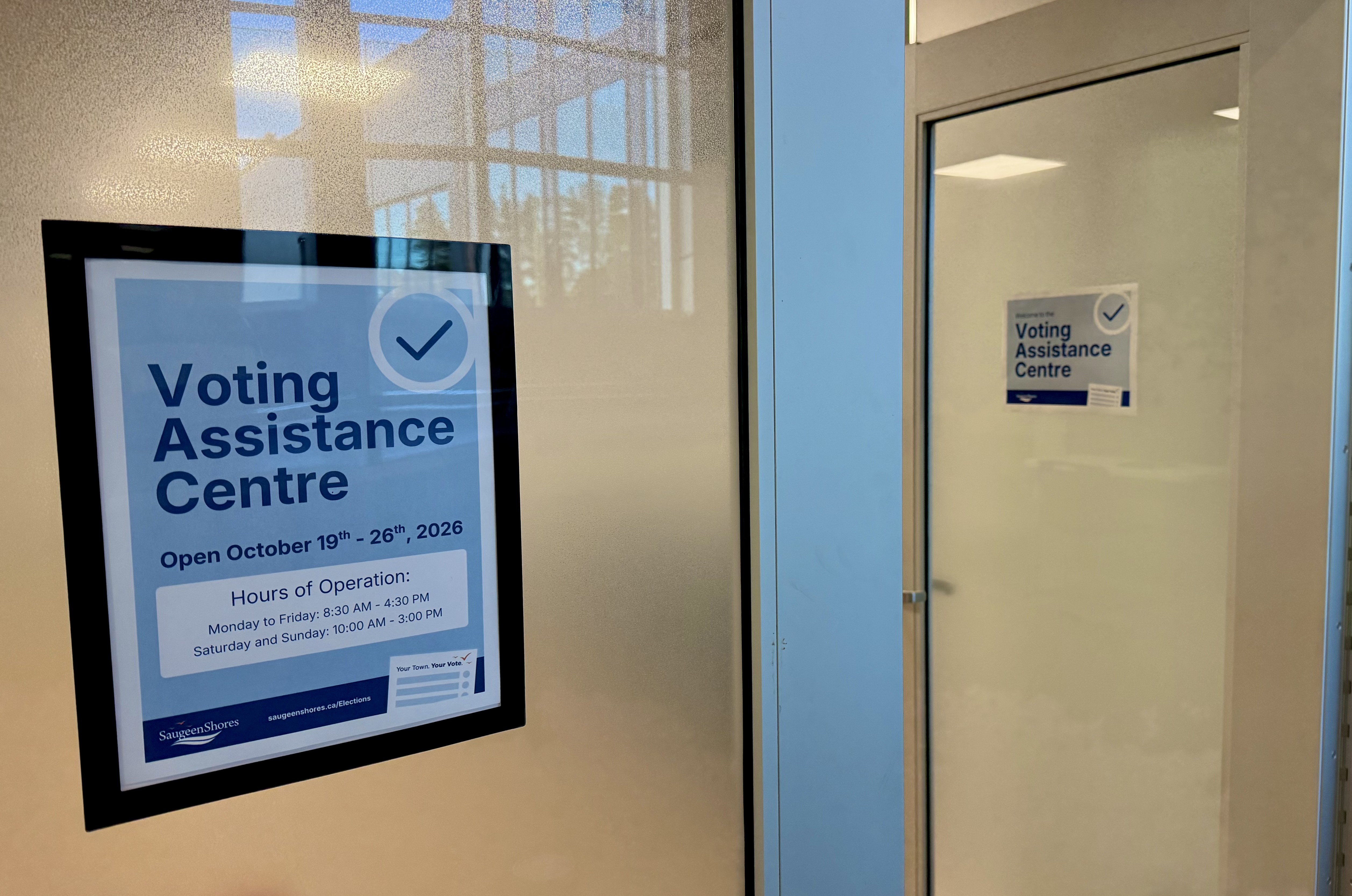 A sign for Voting Assistance Centre on a glass door