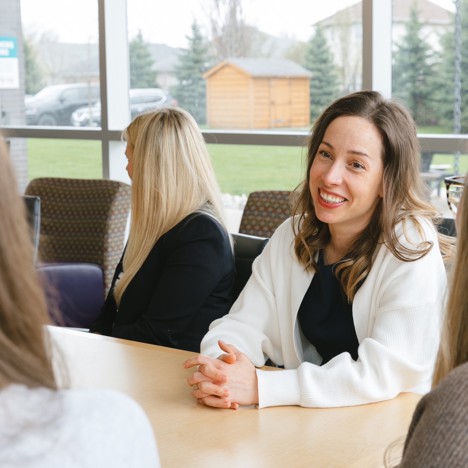 Woman smiling and speaking in a group meeting by a window
