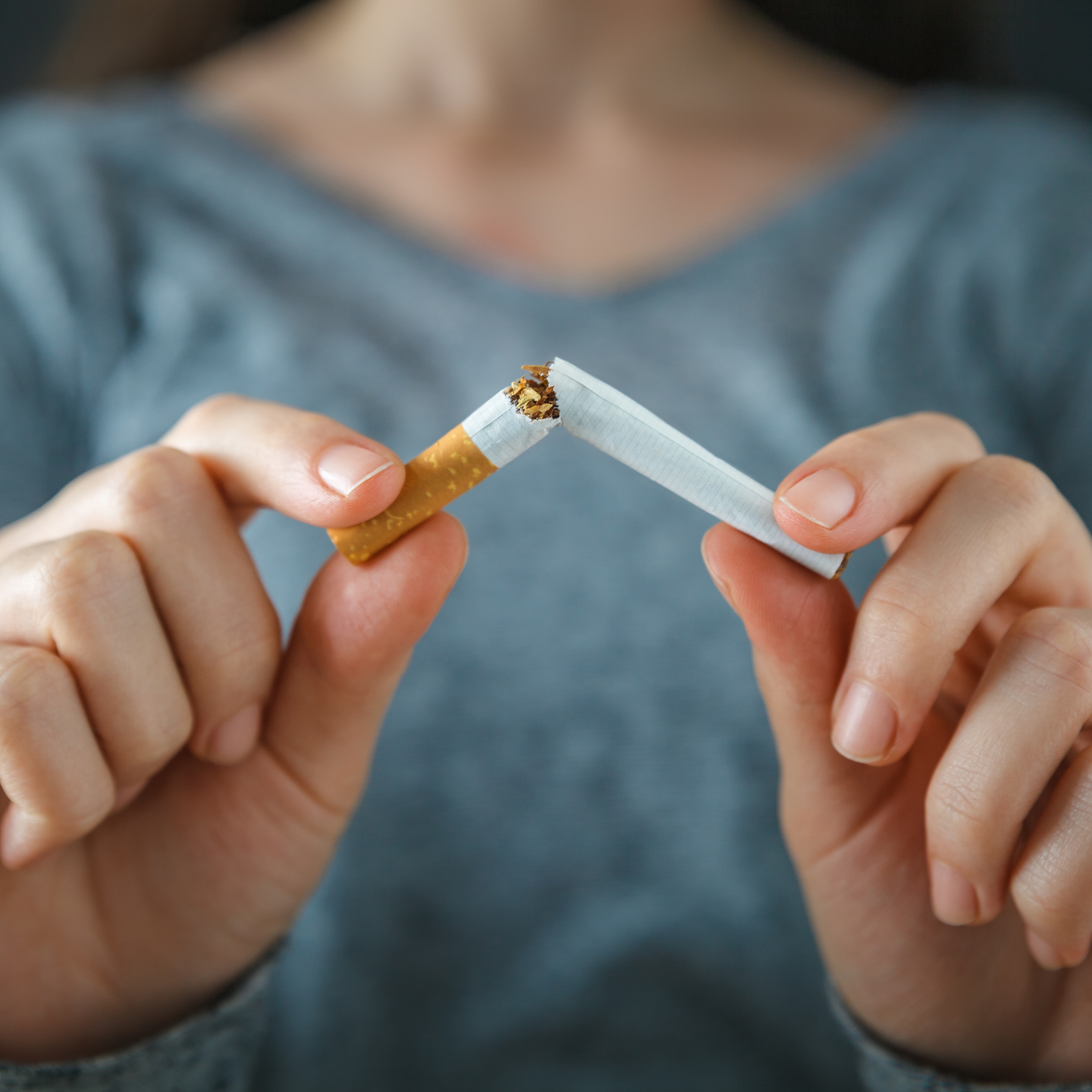 Person breaking a cigarette in half with both hands to symbolize quitting smoking