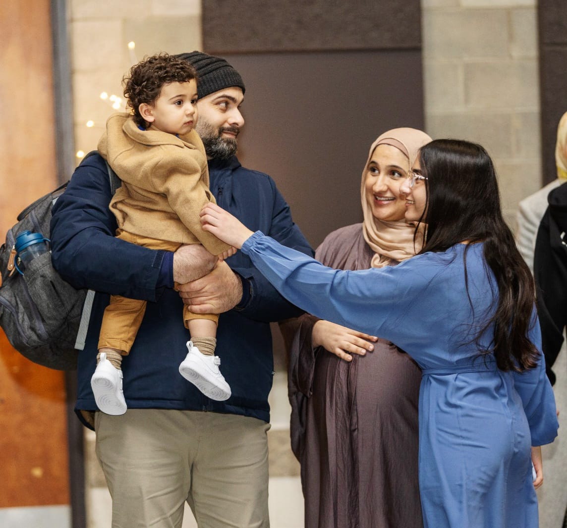 A family smiles at a young child at Sir Frederick Banting Secondary School's annual Iftar gathering hosted by the Muslim Student Association. 