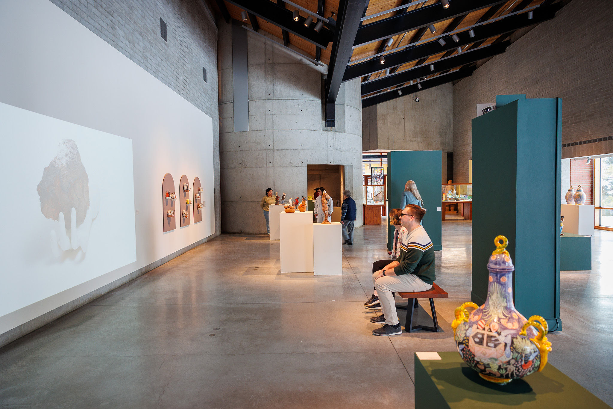A modern art gallery interior with several people observing various art displays.