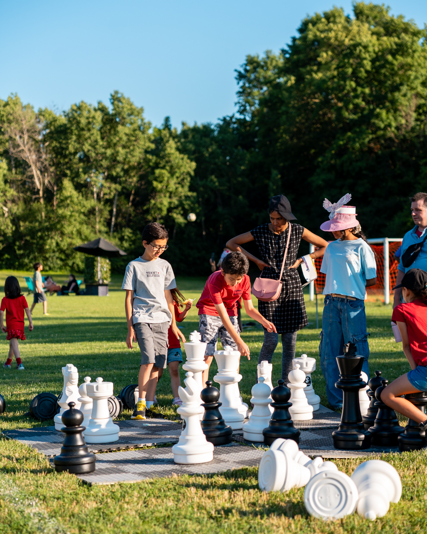 A group of people play a giant game of chess in Waterloo Park on sunny day.